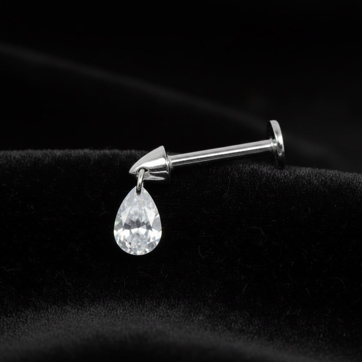 silver  labret stud featuring a sparkling cubic zirconia teardrop charm drop, displayed on a dark moody background for boho goth style
