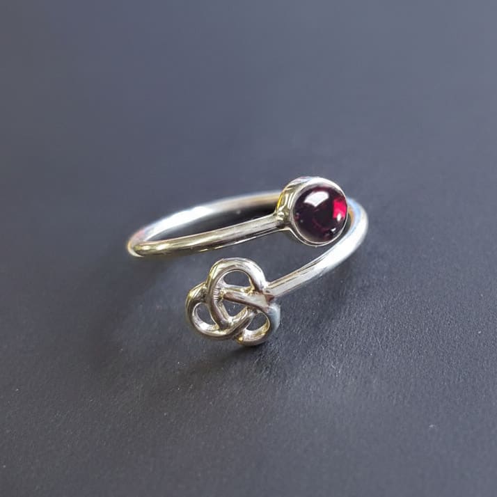 open silver ring with red garnet and Celtic trinity detail 