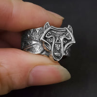 handmade norse viking wolf ring held between models fingers to show the wide chunky band