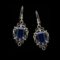 a pair of luxury gothic dangle earrings in silver with dark blue sapphire stones