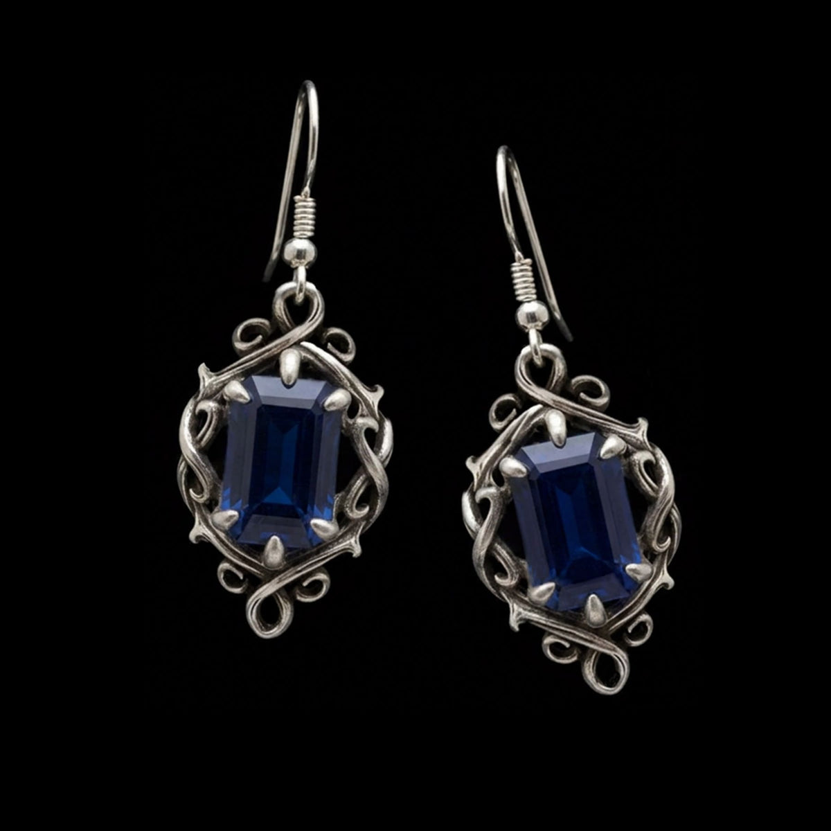 a pair of luxury gothic dangle earrings in silver with dark blue sapphire stones
